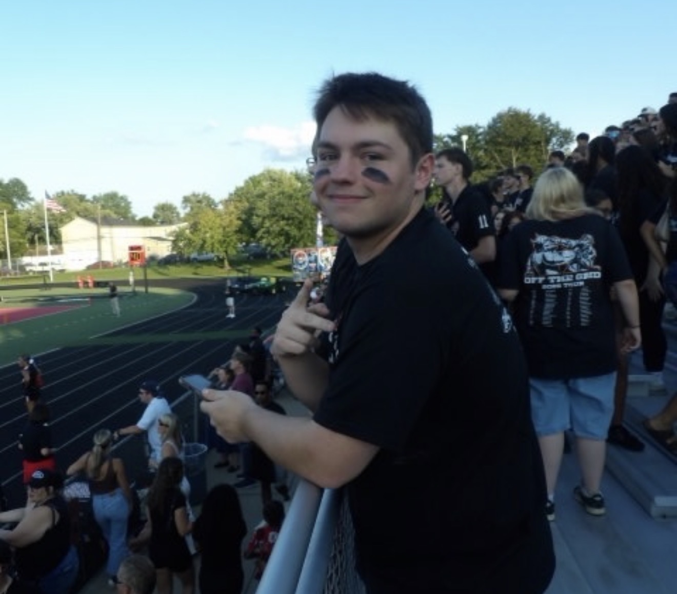 Max Milligan smiling in the stands at a track-and-field event